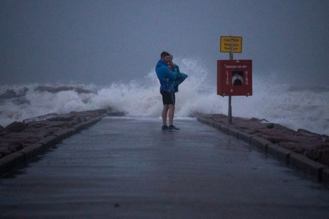 local resident john smith holds his 18 month old son owen as he stands near breaking waves on a pier ahead of the arrival of tropical storm nicholas in galveston texas u s september 13 2021 photo reuters