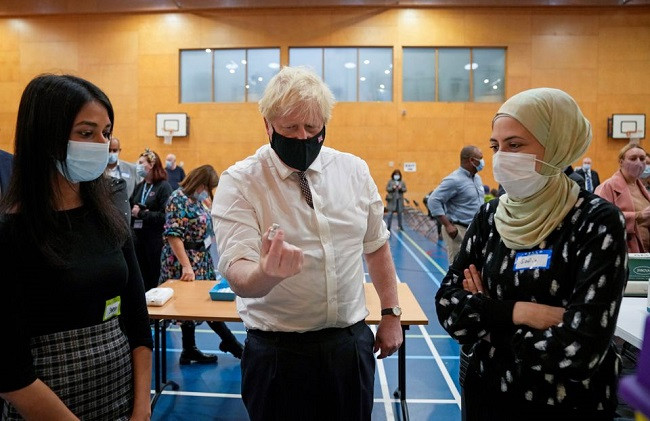 britain s prime minister boris johnson shakes a dose of the pfizer s coronavirus disease covid 19 vaccine as it is diluted before being administered during his visit at a covid 19 vaccination centre at little venice sports centre in london britain october 22 2021 photo reuters