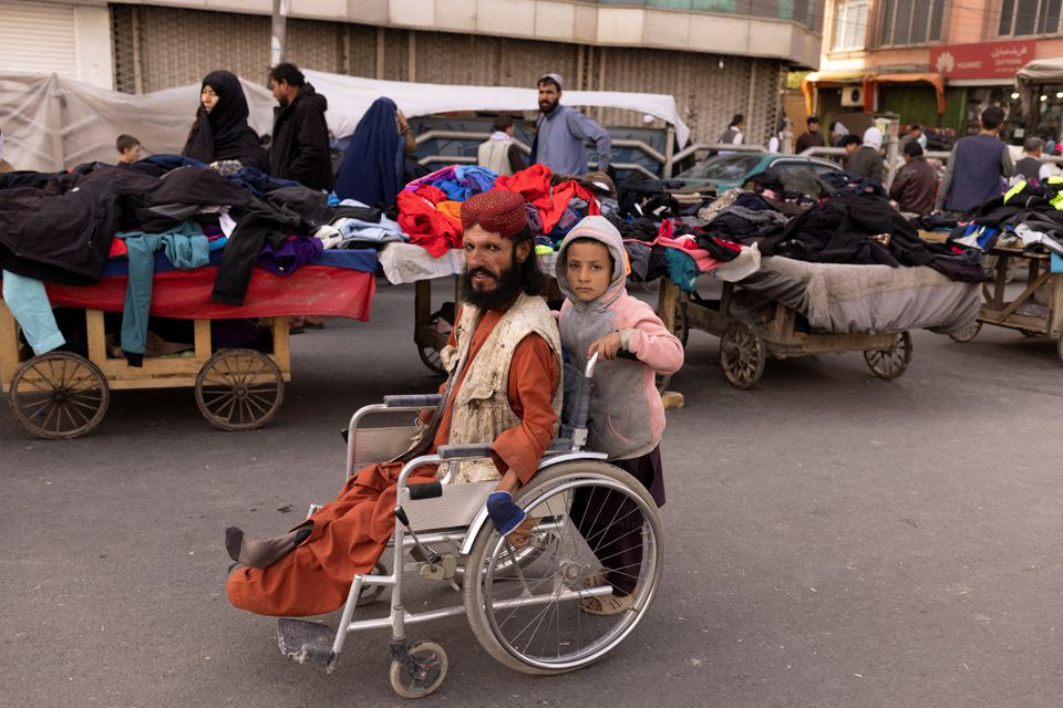 a boy pushes a man s wheelchair on a street in kabul afghanistan october 22 2021 reuters