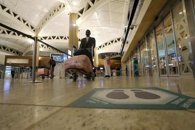 a social distancing sign is seen on the floor as a saudi man man wearing a face mask walks with his luggage at the king khalid international airport after saudi authorities lifted the travel ban on its citizens after fourteen months due to coronavirus disease covid 19 restrictions in riyadh saudi arabia may 16 2021 photo reuters