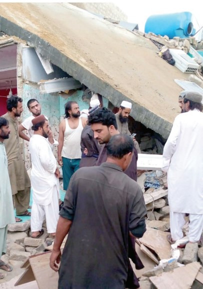 pile of rubble neighbours stand in front of the house which collapsed in the baldia town area of city on tuesday photo express