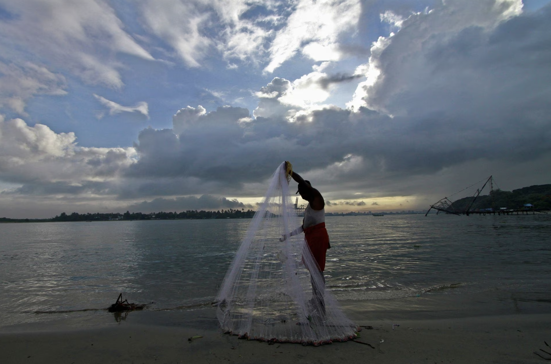 a fisherman arranges his fishing net at a beach against the backdrop of pre monsoon clouds in the southern indian city of kochi june 5 2014 photo reuters file