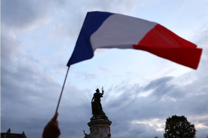 a protesters holds a french national flag as people gather to protest against the french far right rassemblement national national rally   rn party at the place de la republique following partial results in the first round of the early 2024 legislative elections in paris france photo reuters