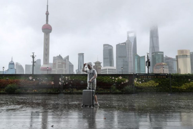 a man with luggage walks in the rain on the bund as typhoon in fa approaches shanghai china july 25 2021 photo reuters a man with luggage walks in the rain on the bund as typhoon in fa approaches shanghai china july 25 2021 photo reuters