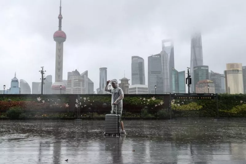 a man with luggage walks in the rain on the bund as typhoon in fa approaches shanghai china july 25 2021 photo reuters a man with luggage walks in the rain on the bund as typhoon in fa approaches shanghai china july 25 2021 photo reuters