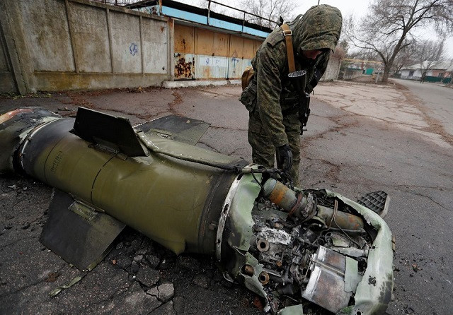 a militant of the self proclaimed donetsk people s republic inspects the remains of a missile that landed on a street in the separatist controlled city of donetsk ukraine february 26 2022 photo reuters