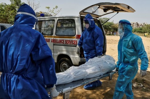 health workers carry the body of a man who died from the coronavirus disease covid 19 for burial at a graveyard in new delhi india april 9 2021 photo reuters