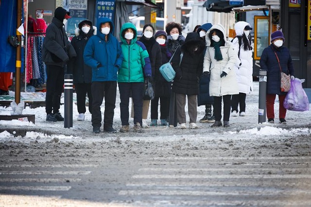 people wearing masks stand before a zebra crossing on a cold winter day amid the coronavirus disease covid 19 pandemic in seoul south korea january 7 2021 photo reuters