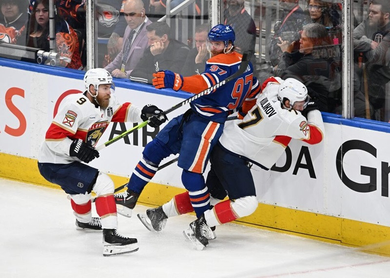 une 21, 2024; Edmonton, Alberta, CAN; Edmonton Oilers center Connor McDavid (97) is checked by Florida Panthers defenseman Dmitry Kulikov (7) and center Sam Bennett (9) in the second period in game six of the 2024 Stanley Cup Final at Rogers Place. PHOTO REUTERS