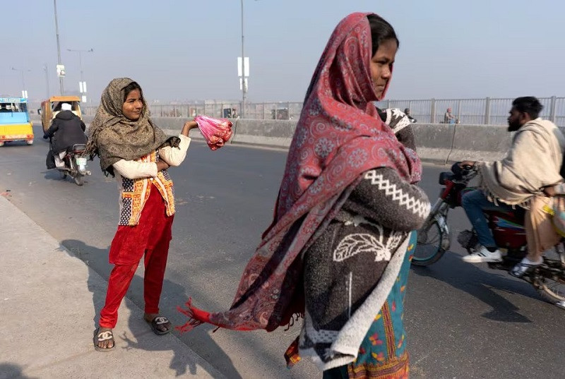 A girl waits for customers while selling meat to feed the birds, as a form of charity to bring good luck and ward off adversity, along Ravi Bridge in Lahore, Pakistan December 19, 2023. PHOTO: REUTERS