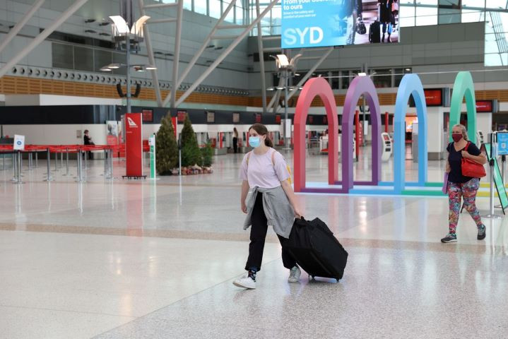 people wearing masks walk through a mostly empty domestic terminal at sydney airport in sydney australia december 21 2020 reuters loren elliott file photo