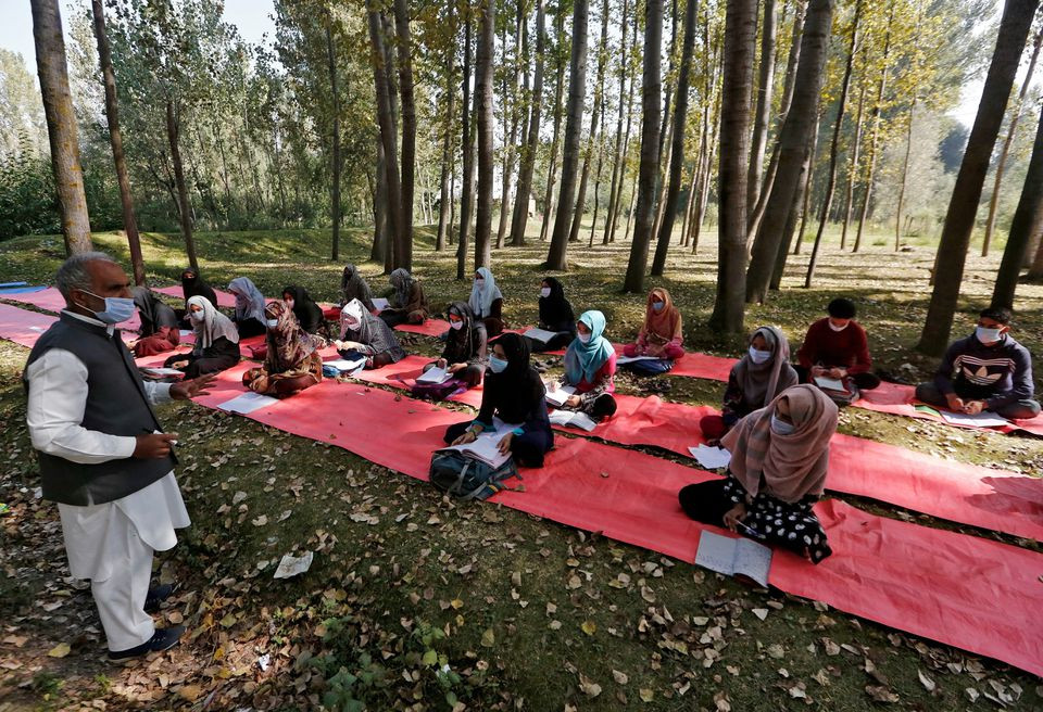 students wearing masks attend their class under the trees as they maintain social distancing outside their school amid the coronavirus disease covid 19 outbreak in gund on the outskirts of srinagar september 30 2020 photo reuters