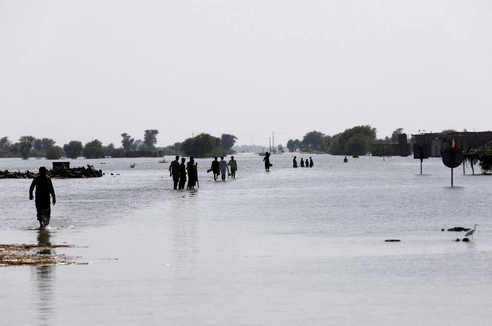 people walk amid rising flood waters on the indus highway following rains and floods during the monsoon season in mehar pakistan august 31 2022 reuters