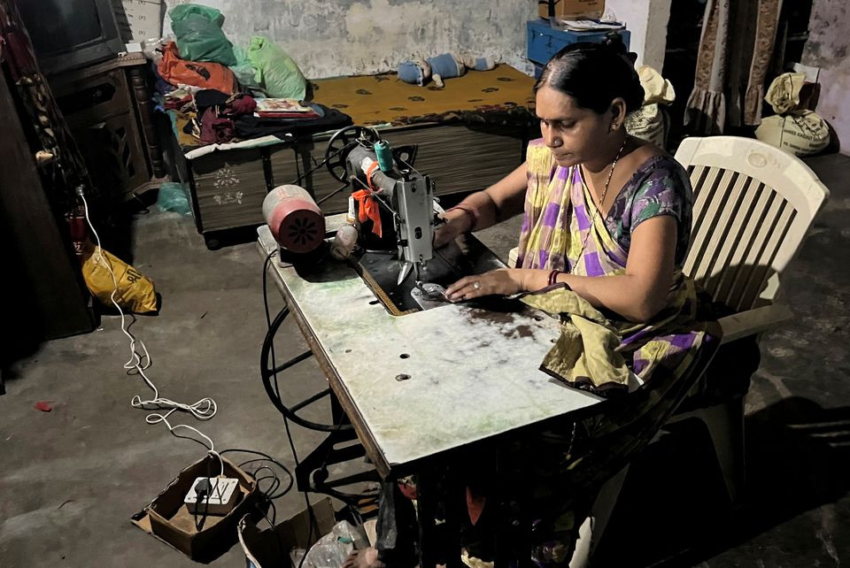 Reena Ben works on a solar-powered sewing machine to stitch clothes inside her one-room house in Modhera, India's first round-the-clock solar-powered village, in the western state of Gujarat, India, October 19, 2022. REUTERS