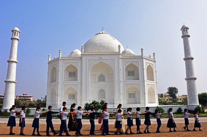 in this photograph taken on nov 25 2021 school children walk past a replica of the taj mahal during their visit at burhanpur in india s madhya pradesh state photo afp