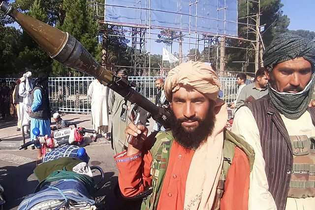 a taliban fighter holds a rocket propelled grenade rpg along the roadside in herat afghanistan s third biggest city after government forces pulled out following weeks of being under siege photo afp