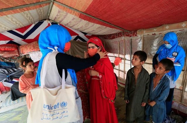 A UNICEF worker helps an internally displaced girl put on a face mask at a makeshift camp, amid the coronavirus disease (Covid-19) outbreak, in Jalalabad, Afghanistan June 22, 2020. PHOTO: REUTERS