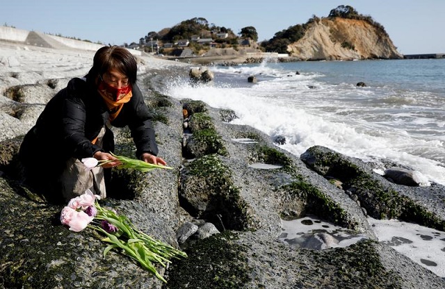 mariko odawara places flowers to mourn the victims of the earthquake and tsunami that killed thousands and triggered the worst nuclear accident since chernobyl during its 10th anniversary in iwaki fukushima prefecture japan march 11 2021 photo reuters