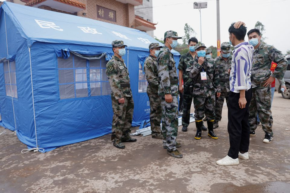 militia members speak with a manager at the entrance of lu village near the site where a china eastern airlines boeing 737 800 plane flying from kunming to guangzhou crashed in wuzhou guangxi zhuang autonomous region china march 22 2022 reuters