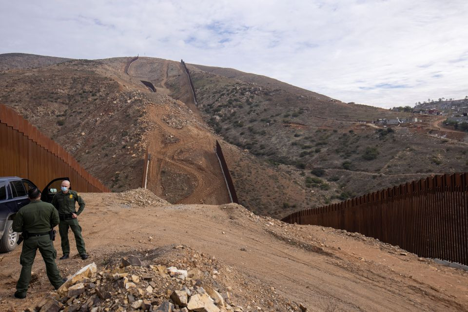 us border patrol agents stand near the location of halted construction along the us border wall with mexico as an unfinished section is shown on otay mountain east of san diego california photo reuters