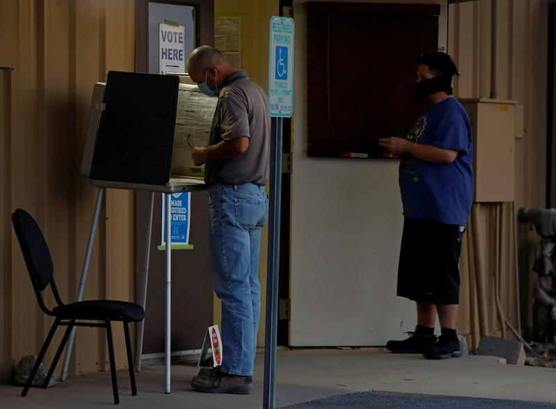 a voter fills in his ballot at a polling booth as another voter waits in line on election day at a polling station in marana arizona us november 3 2020 photo reuters