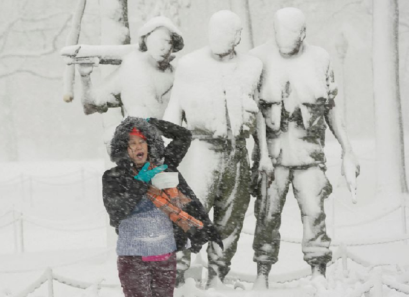 a woman poses for a photograph beneath a snow covered statue at the vietnam veterans memorial on the national mall in washington us january 3 2022 photo reuters