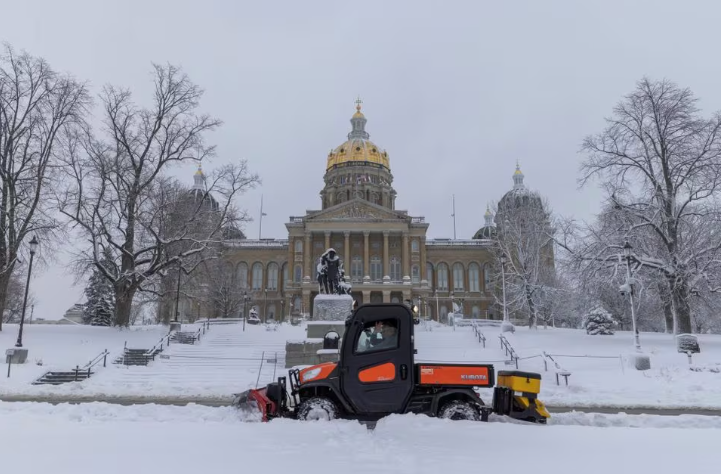 workers remove snow from the sidewalk outside of the iowa state capitol building after a snowstorm left several inches of snow in des moines iowa u s january 9 2024 photo reuters