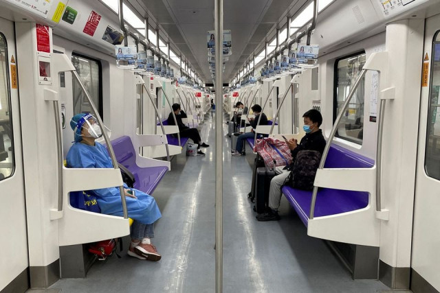 a passenger in a protective suit rides on a subway train on the first day of parts of city s subway services resumed following the coronavirus disease covid 19 outbreak in shanghai china may 22 2022 reuters