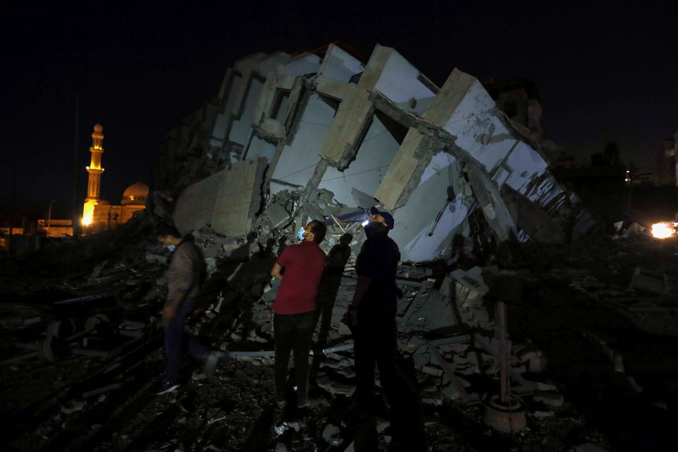 Palestinians look on as they stand at the site where a building was destroyed by Israeli air strikes amid a flare-up of Israeli-Palestinian violence, in Gaza City May 11, 2021. PHOTO: REUTERS