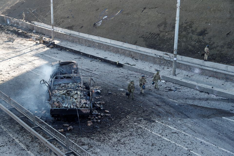 ukrainian servicemen walk by a damaged vehicle at the site of a fighting with russian troops after russia launched a massive military operation against ukraine in kyiv ukraine february 26 2022 photo reuters