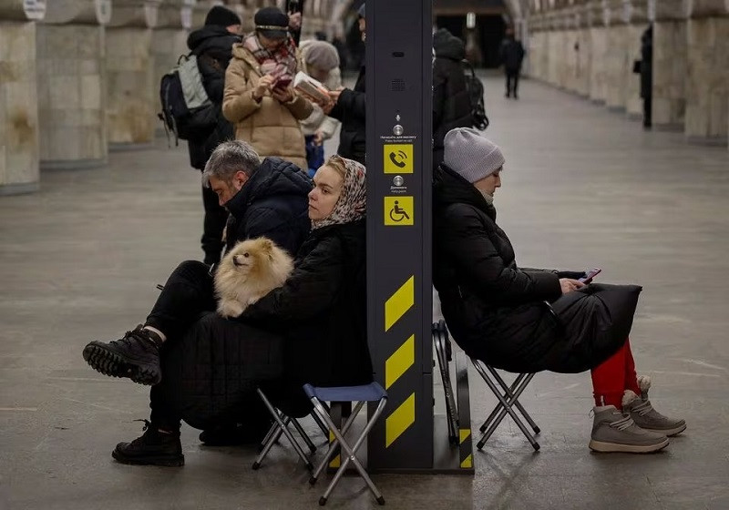 a woman sits with her dog on a chair as people take shelter inside a metro station during an air raid alert in kyiv ukraine january 13 2024 photo reuters