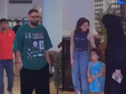 badshah stares on the sidelines as hania aamir poses with fans at dubai airport