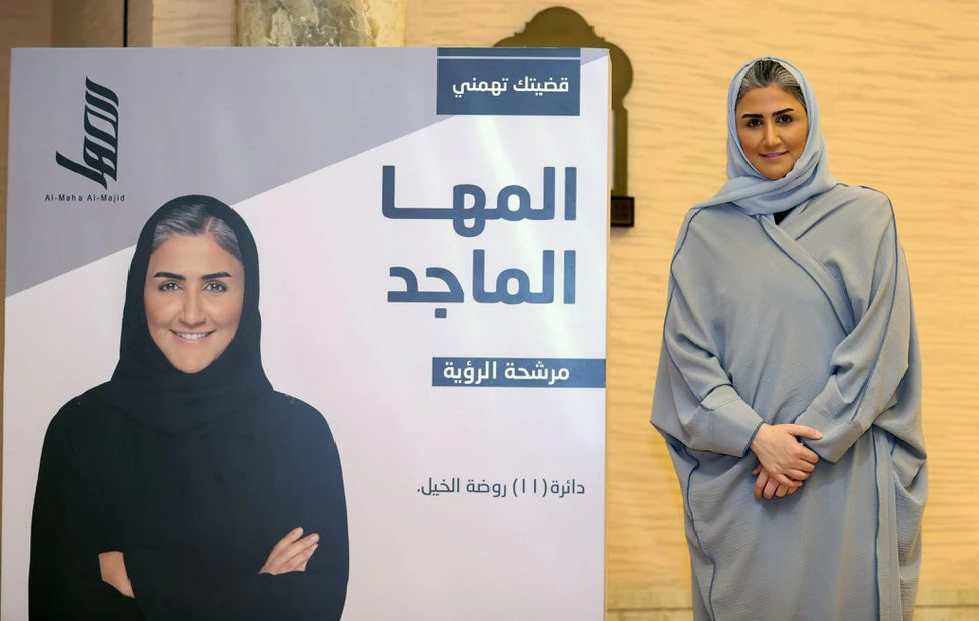 al maha al majid a candidate in qatar s shura council election poses for a photo next to an election poster in doha qatar september 30 2021 picture taken september 30 2021 reuters