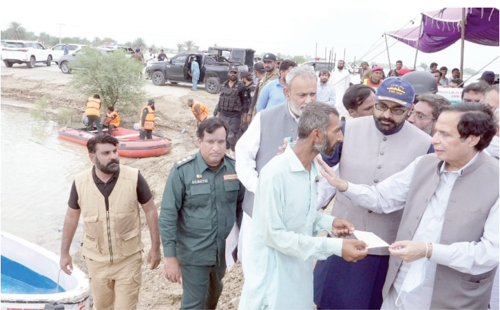 on the ground punjab cm chaudhry pervaiz elahi hands over a cheque to a flood victim in rajanpur district photo express