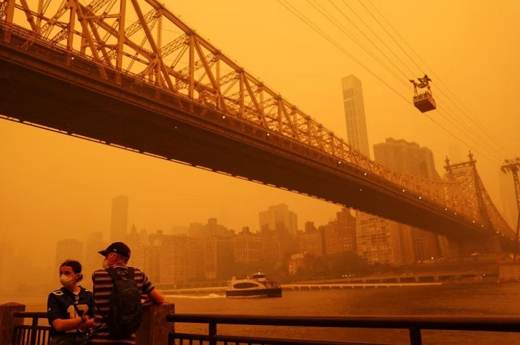 people wear protective masks as the roosevelt island tram crosses the east river while haze and smoke from the canadian wildfires shroud the manhattan skyline june 7 2023 photo reuters