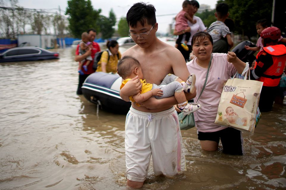 a man holding a baby wades through a flooded road following heavy rainfall in zhengzhou henan province china july 22 2021 photo reuters file