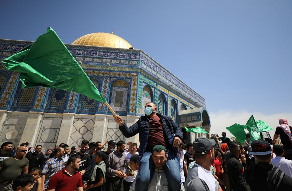 people hold hamas flags as palestinians gather after performing the last friday of ramadan to protest over the possible eviction of several palestinian families from homes on land claimed by jewish settlers in the sheikh jarrah neighbourhood in jerusalem s old city may 7 2021 reuters