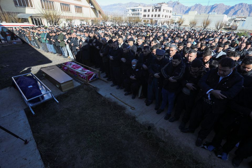 people pray next to bodies of iraqi kurdish migrants who drowned while trying to cross the channel between france and britain in the town of rania sulaimaniyah province iraq december 26 2021 reuters