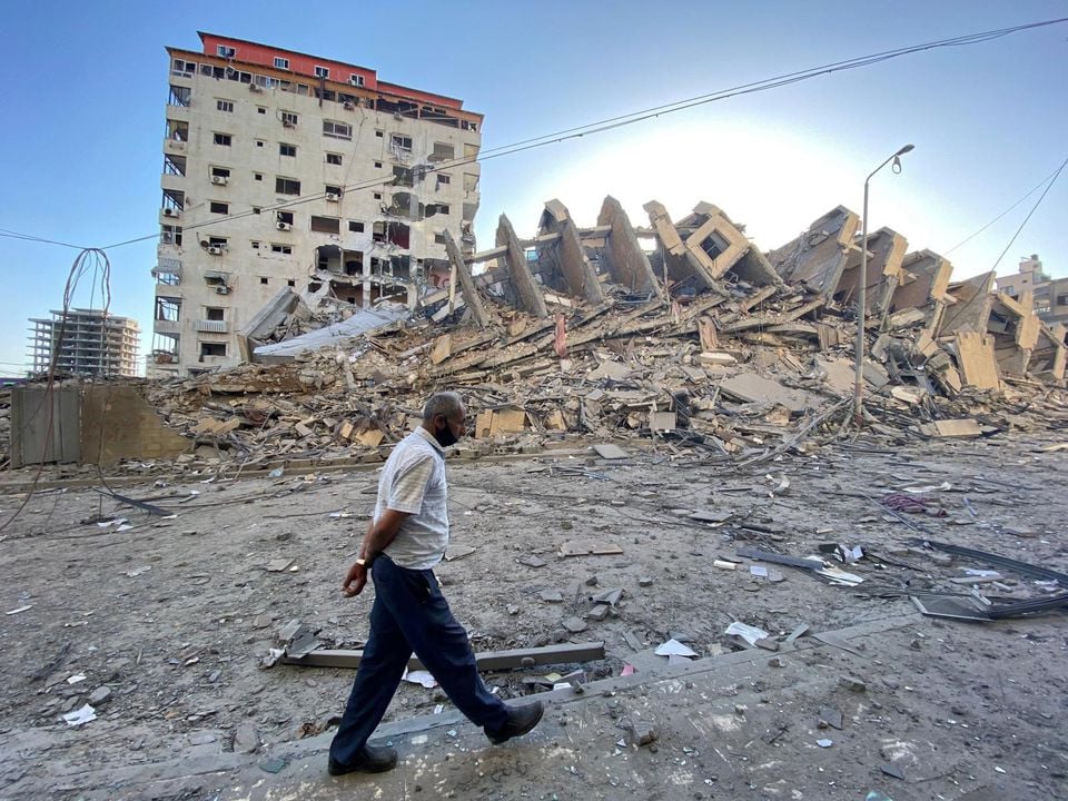 A Palestinian man walks past a tower building which was destroyed in Israeli air strikes, amid a flare-up of Israeli-Palestinian violence, in Gaza City May 12. PHOTO: REUTERS