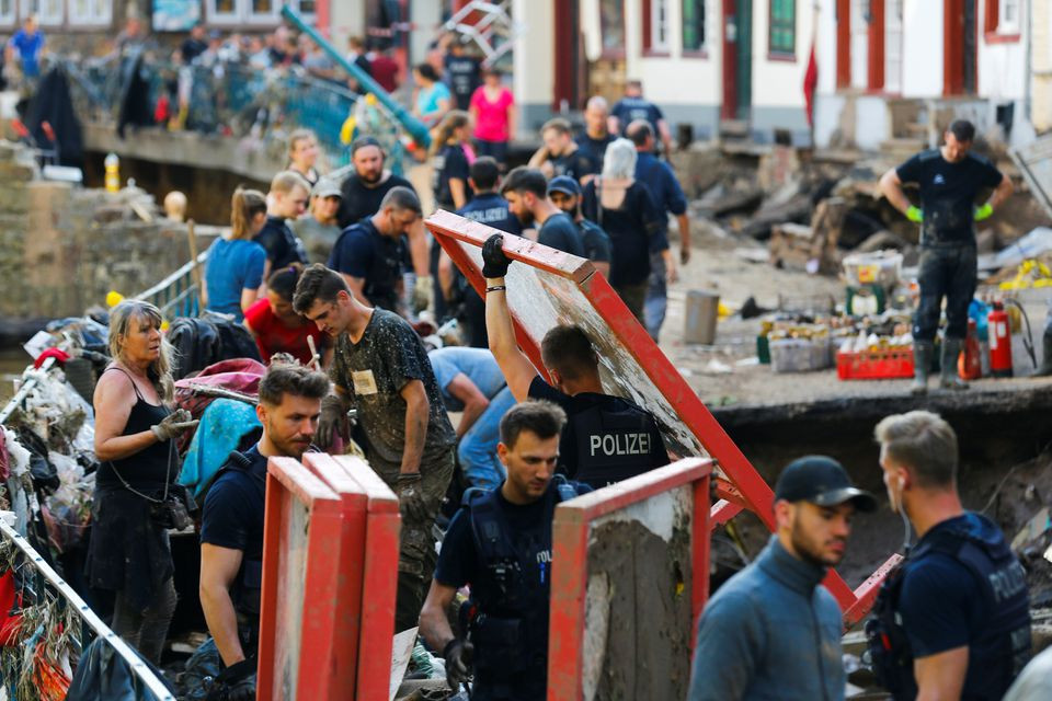 police officers and volunteers clean rubble in an area affected by floods caused by heavy rainfalls in bad muenstereifel germany july 18 2021 photo reuters