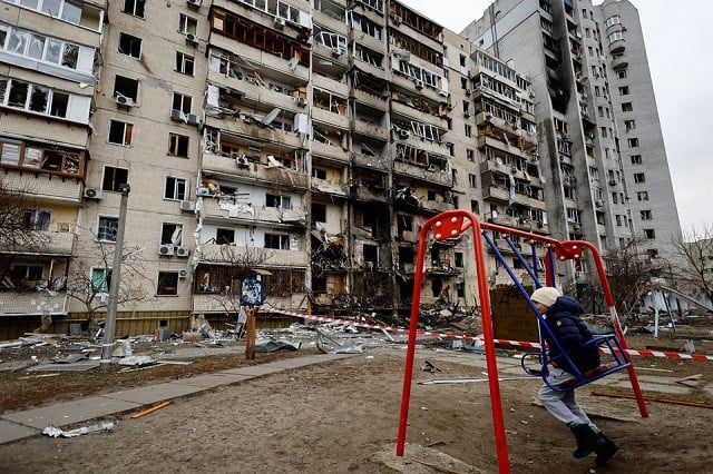 a child sits on a swing in front of a damaged residential building after russia launched a massive military operation against ukraine in kyiv ukraine february 25 2022 photo reuters