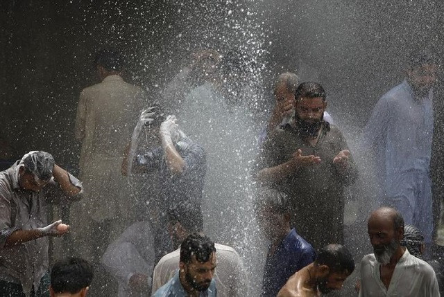 people are seen bathing while others cool off from the heat as they are sprayed with water jetting out from a leaking water pipeline in karachi june 25 2015 photo reuters