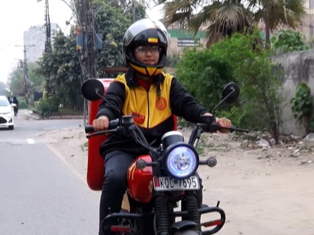 a female food delivery driver poses for a picture photo express