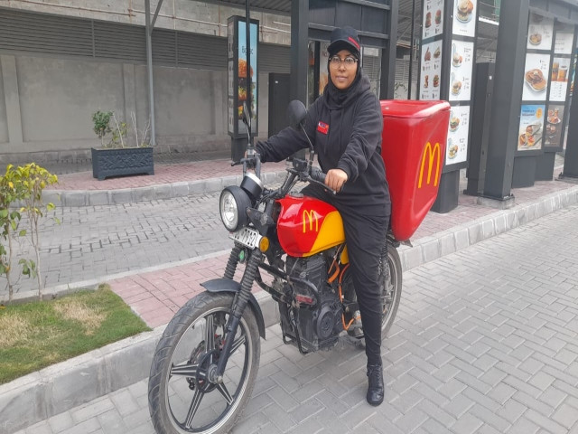 a female food delivery driver poses for a picture photo express