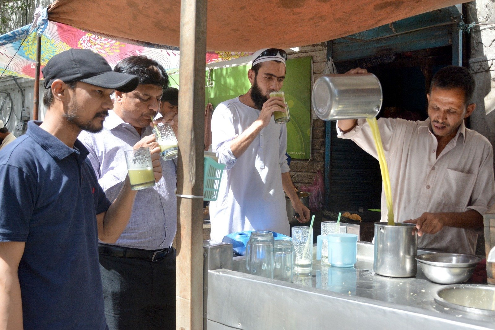 people drink chilled sugarcane juice along a street in karachi to avoid heat exhaustion on a hot summer day photo express