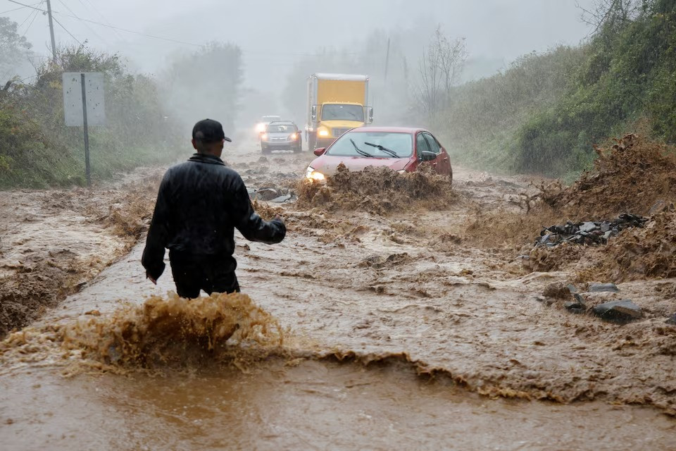 a local resident walks out into fast flowing waters to assist a stranded driver in a stretch of flooded road as tropical storm helene strikes on the outskirts of boone north carolina us on september 27 2024 photo reuters