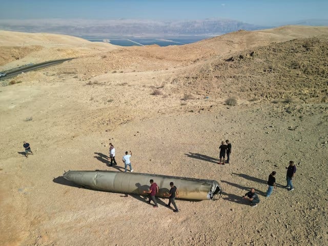 a drone view shows people stand around apparent remains of a ballistic missile lying in the desert following an attack by iran on israel near the southern city of arad israel on october 2 2024 photo reuters