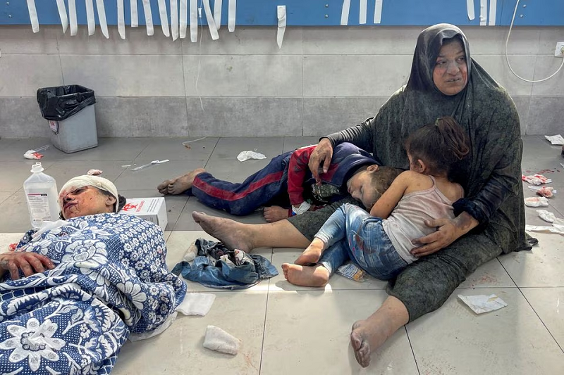 A Palestinian woman holds her children, who were wounded along with her in an Israeli strike, at Shifa hospital in Gaza City, October 23. PHOTO: REUTERS