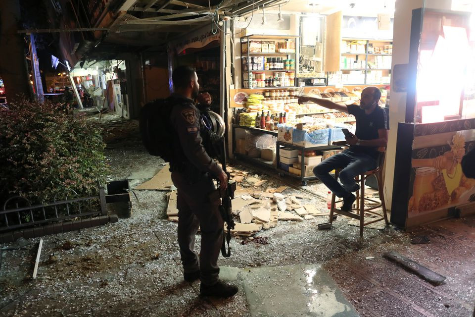 A member of the security forces speaks with a man at the scene where a rocket launched from the Gaza Strip hit, in Holon, Israel May 11, 2021. PHOTO: REUTERS