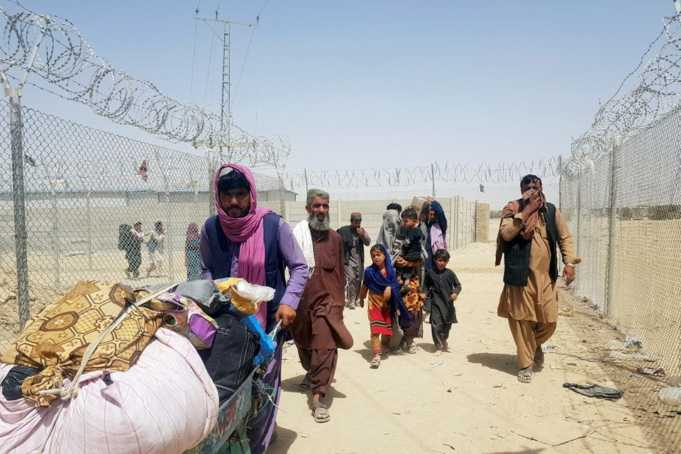a family from afghanistan walk next to fence to cross into pakistan at the friendship gate crossing point in the pakistan afghanistan border town of chaman pakistan september 6 2021 photo reuters